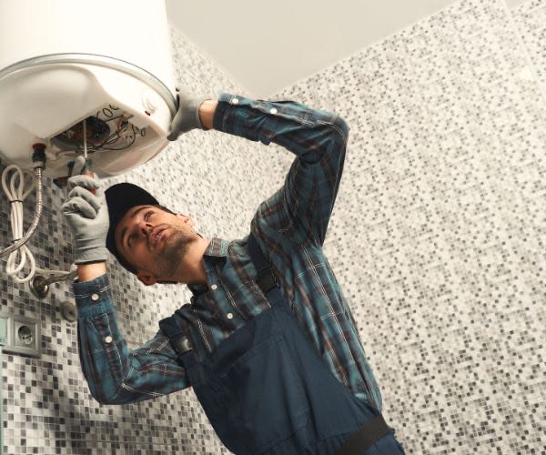 Installateur bei der Wartung eines Warmwasserboilers im Bad